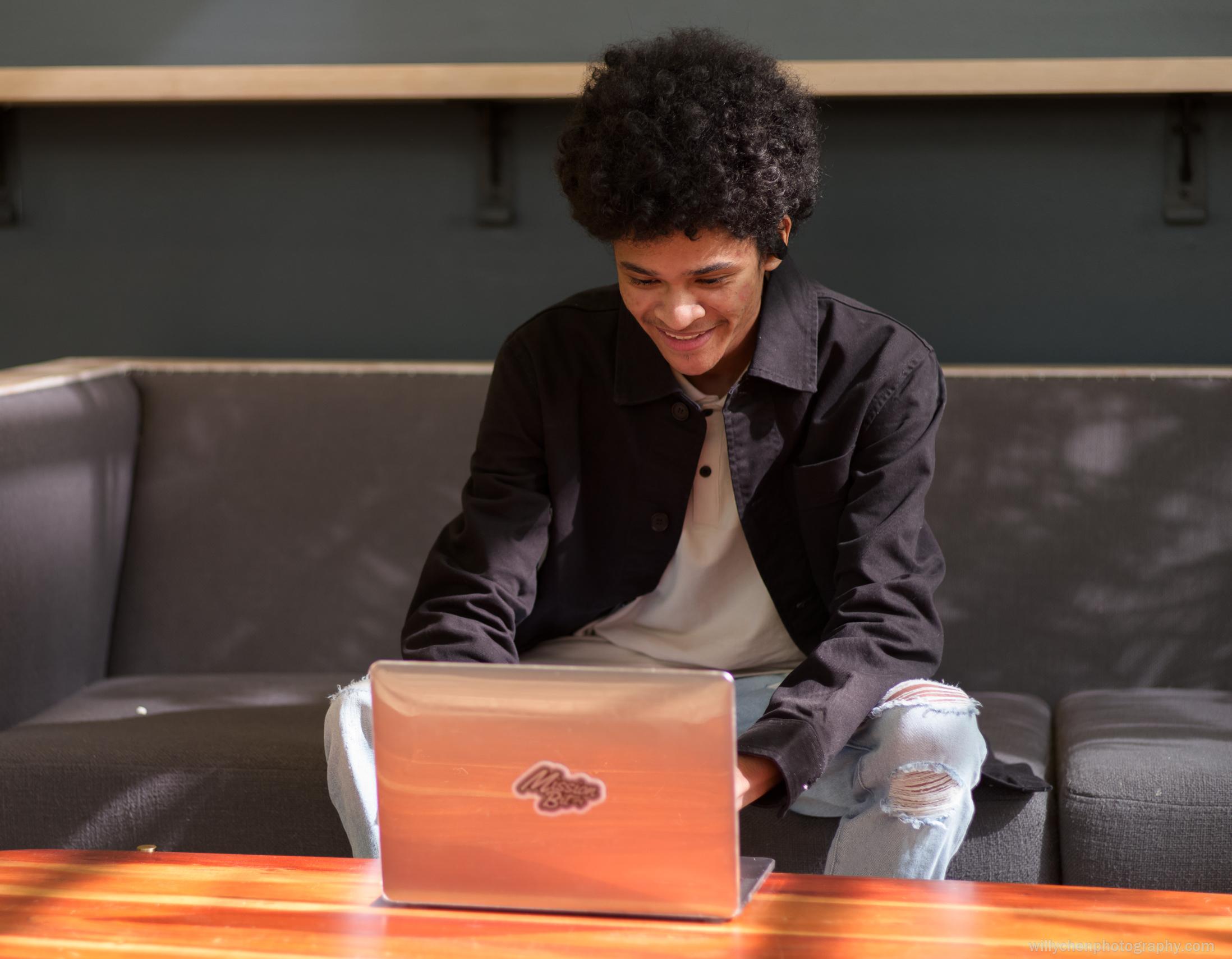 Student on a computer sitting on the couch.